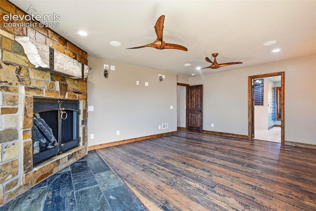 Image 17 of 40: Stone-clad fireplace with a distressed wood mantle
