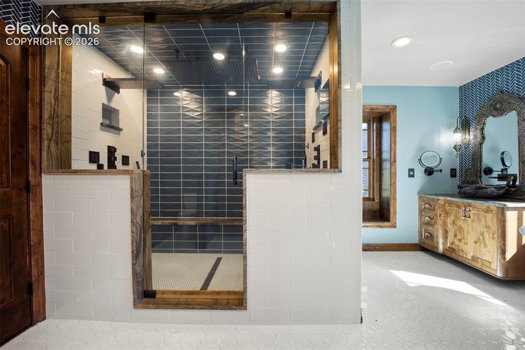 Image 20 of 40: Walk-in shower featuring glass enclosure, large format blue tile, white sub
