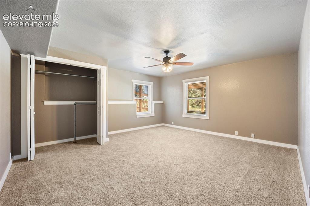 Image 29 of 40: Spacious room featuring neutral carpeting, two windows with white trim, a c