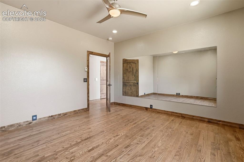 Image 32 of 40: Spacious room featuring wood-finish flooring, a built-in mirrored alcove, a