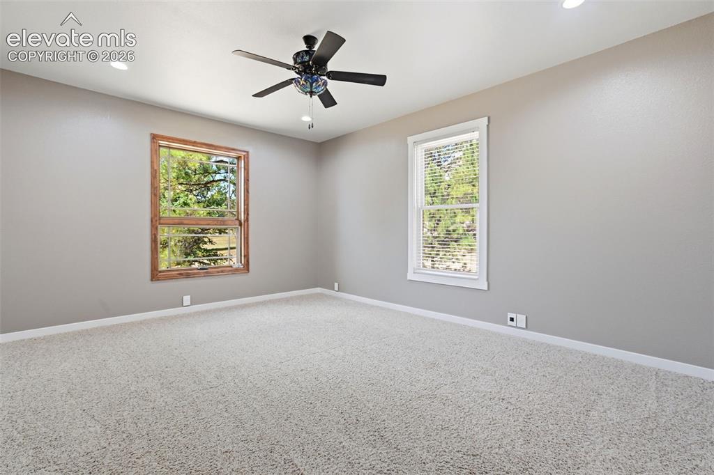 Image 33 of 40: Spacious room featuring neutral carpeting, a ceiling fan with integrated li