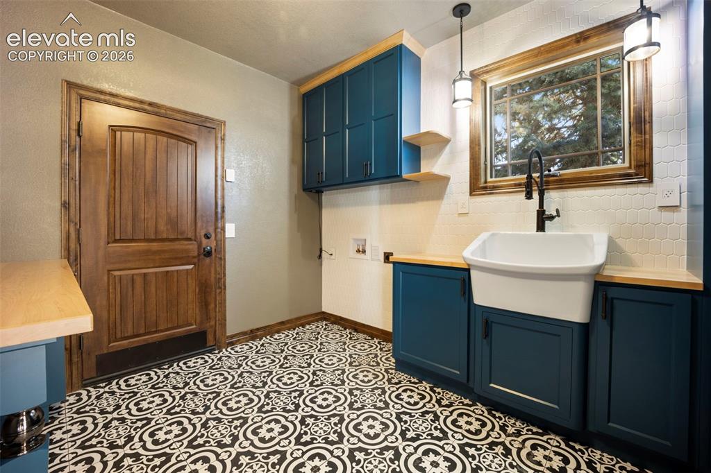 Image 37 of 40: Utility space featuring patterned floor tiles, a deep apron-front sink with