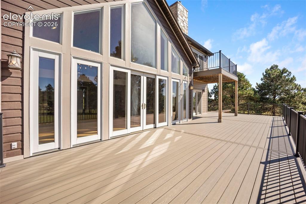 Image 39 of 40: Expansive outdoor deck featuring composite decking, black metal railings, a