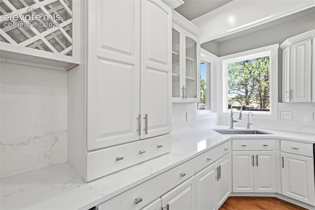 Image 9 of 40: Kitchen featuring white shaker-style cabinetry, a built-in wine rack, light