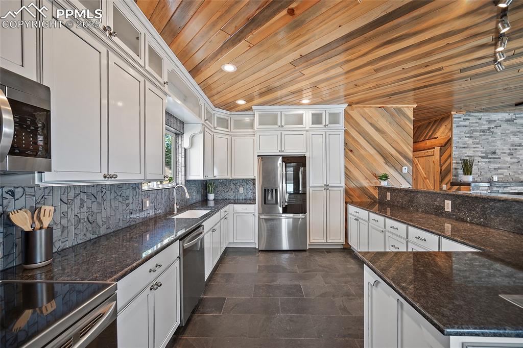 Image 10 of 50: Front view of kitchen featuring custom tongue and groove wood panel ceiling