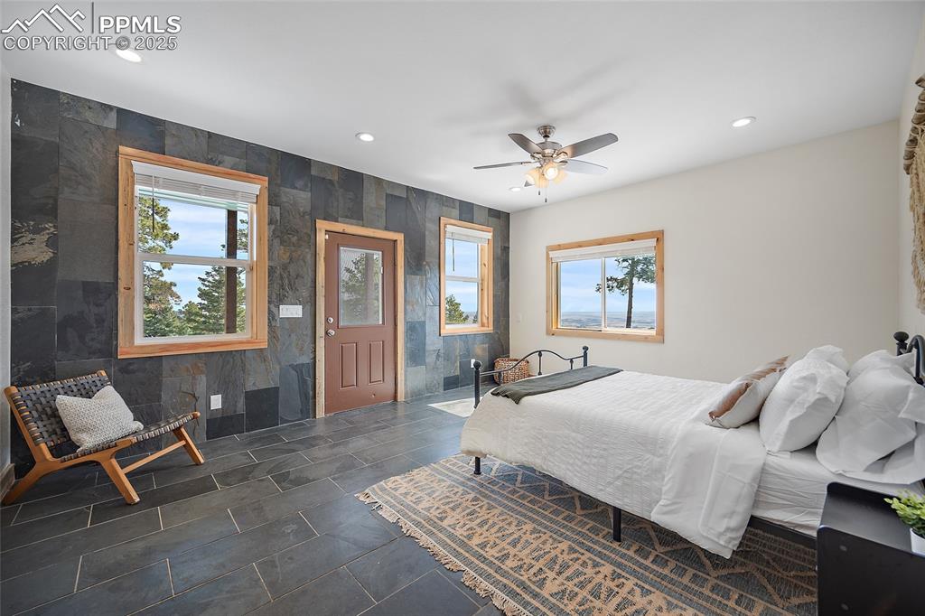 Image 12 of 50: Spacious primary suit featuring custom stone slate accent wall with panoram