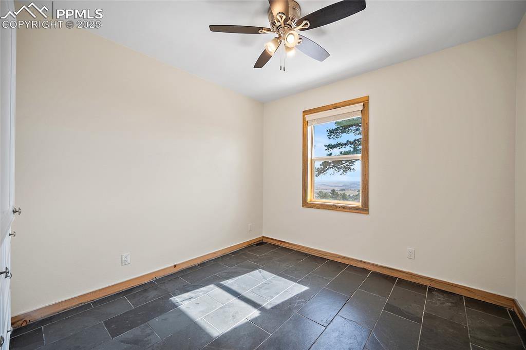 Image 22 of 50: Second bedroom on main floor featuring natural slate flooring and beautiful