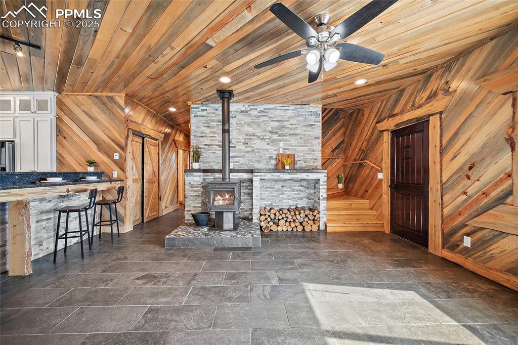 Image 7 of 50: View of living room featuring wood burning stove, built-in, and custom tong
