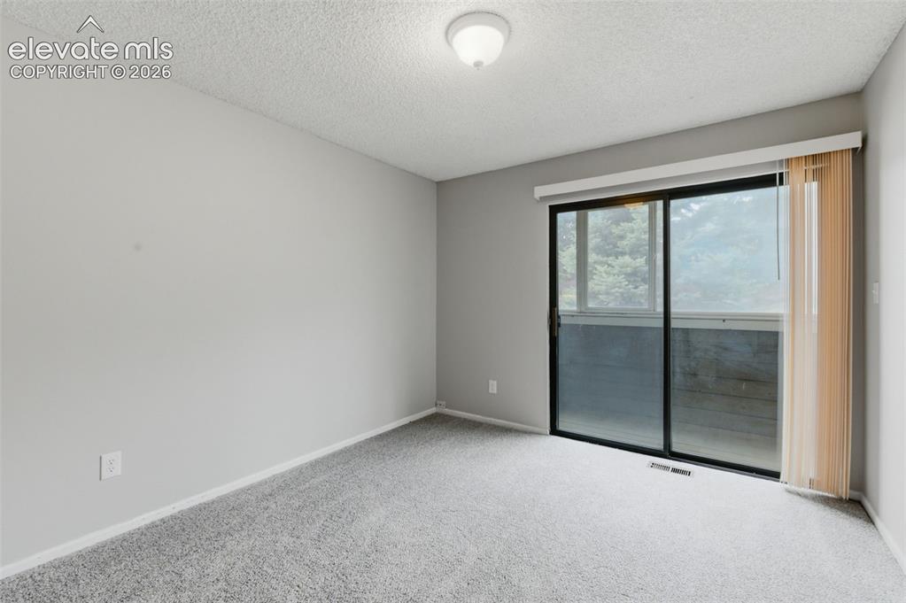 Image 20 of 31: 2nd bedroom with doors to enclosed balcony.
