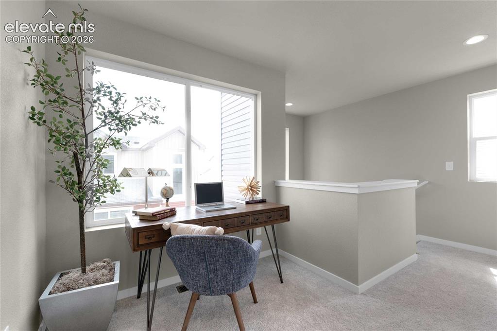 Image 8 of 34: Large window, recessed lighting, carpeted flooring, and a built-in half-wal
