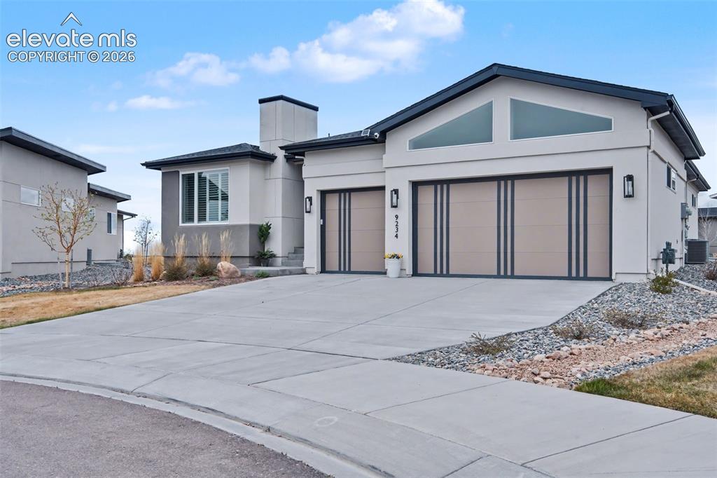 Image 1 of 41: View of front facade featuring a garage, stucco siding, driveway, and a chi