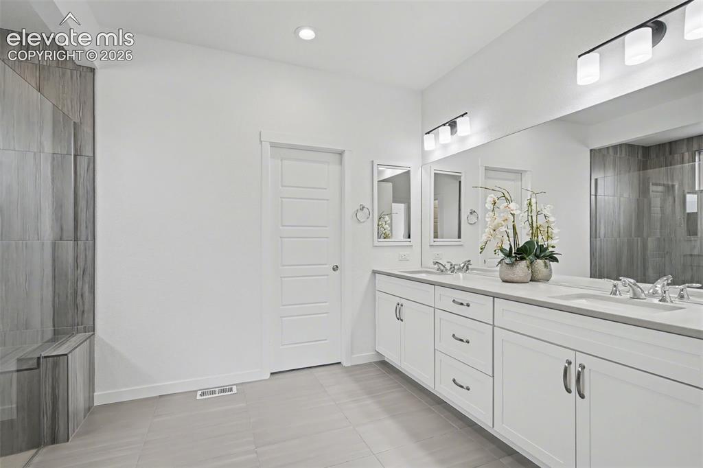 Image 15 of 41: Kitchen with white cabinetry, range hood, stainless steel appliances, decor