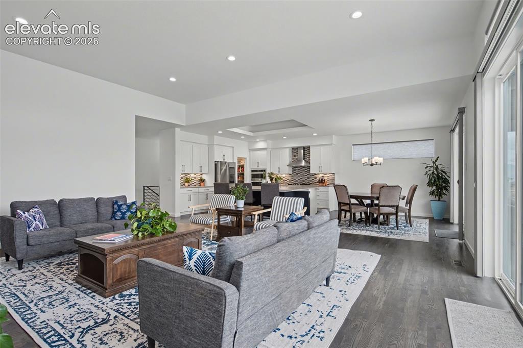 Image 4 of 41: Living area featuring dark wood-type flooring, recessed lighting, and a rai