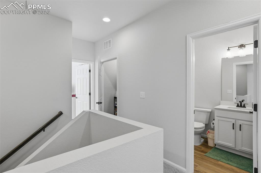 Image 14 of 28: Hallway with an upstairs landing, light wood finished floors, and recessed 