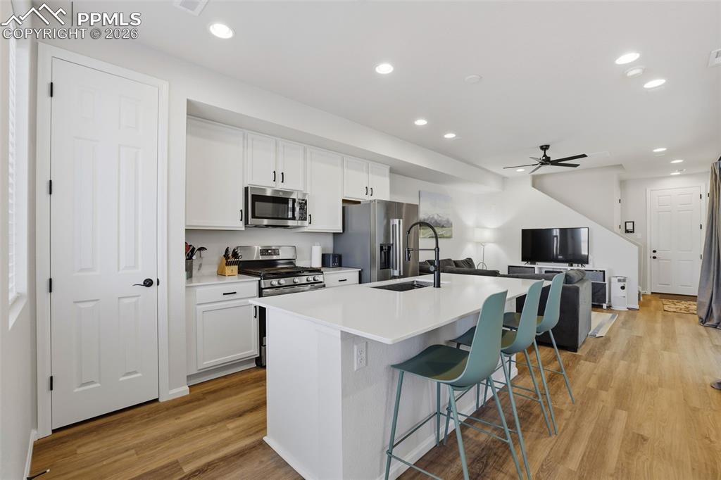 Image 3 of 28: Kitchen featuring recessed lighting, white cabinets, a breakfast bar area, 