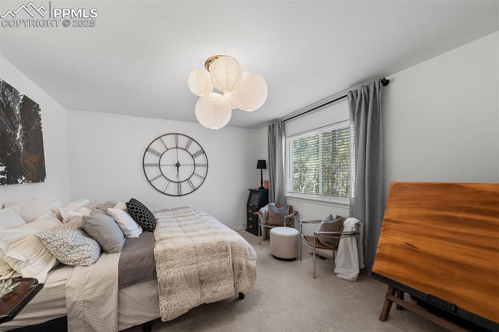 Image 16 of 30: Upper level bedroom with carpeted floors overlooks backyard.