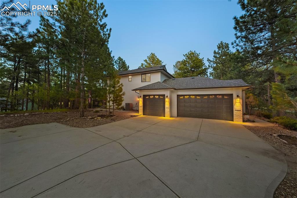Image 28 of 30: Three car garage with paved driveway and extra parking.