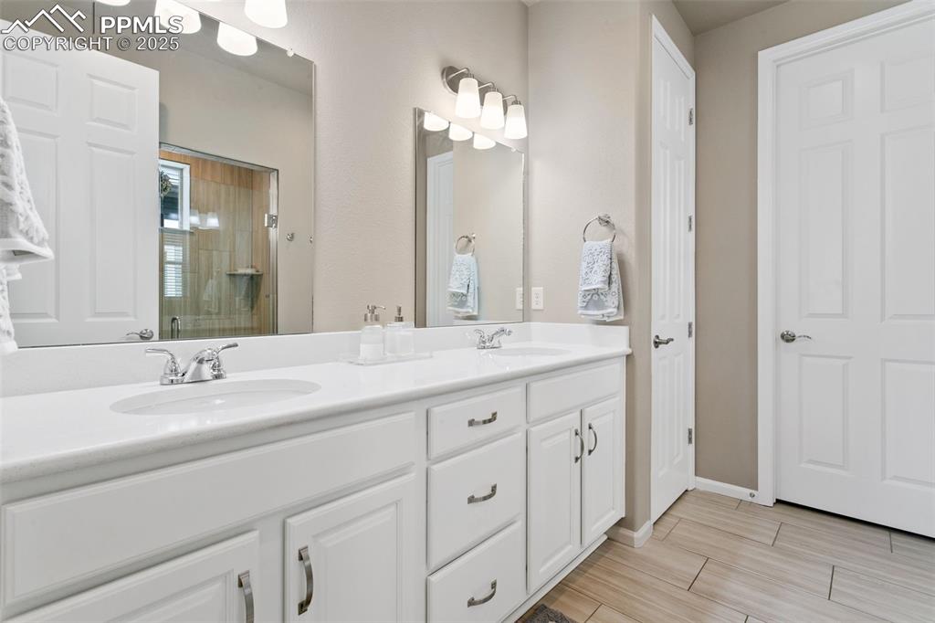 Image 17 of 35: Primary bathroom features quartz countertops, double vanity, zero-entry sho