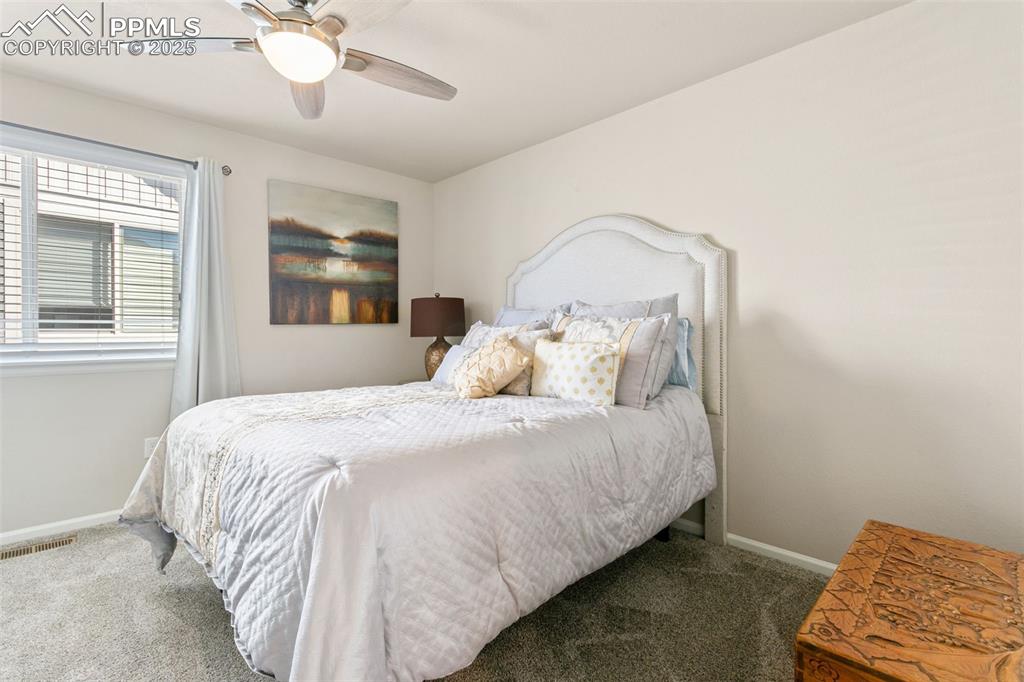 Image 25 of 35: A third bedroom on the upper level features a walk-in closet and ceiling fa
