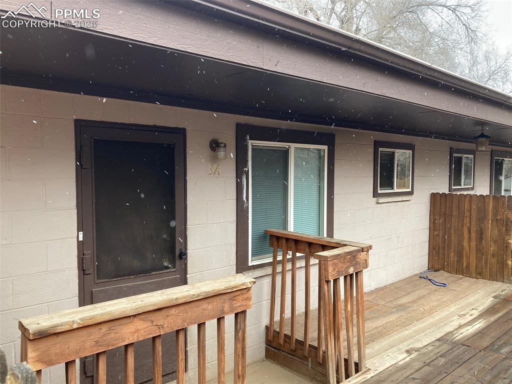 Image 2 of 11: Doorway to property with concrete block siding and a deck