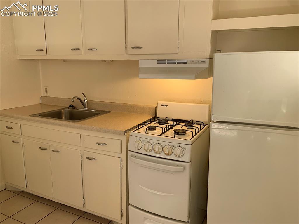 Image 5 of 11: Kitchen featuring white appliances, white cabinets, under cabinet range hoo