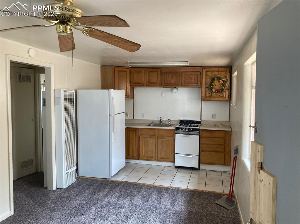 Image 7 of 11: Kitchen with light countertops, light carpet, brown cabinets, and white app