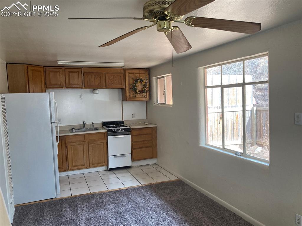 Image 8 of 11: Kitchen featuring white appliances, brown cabinetry, light colored carpet,
