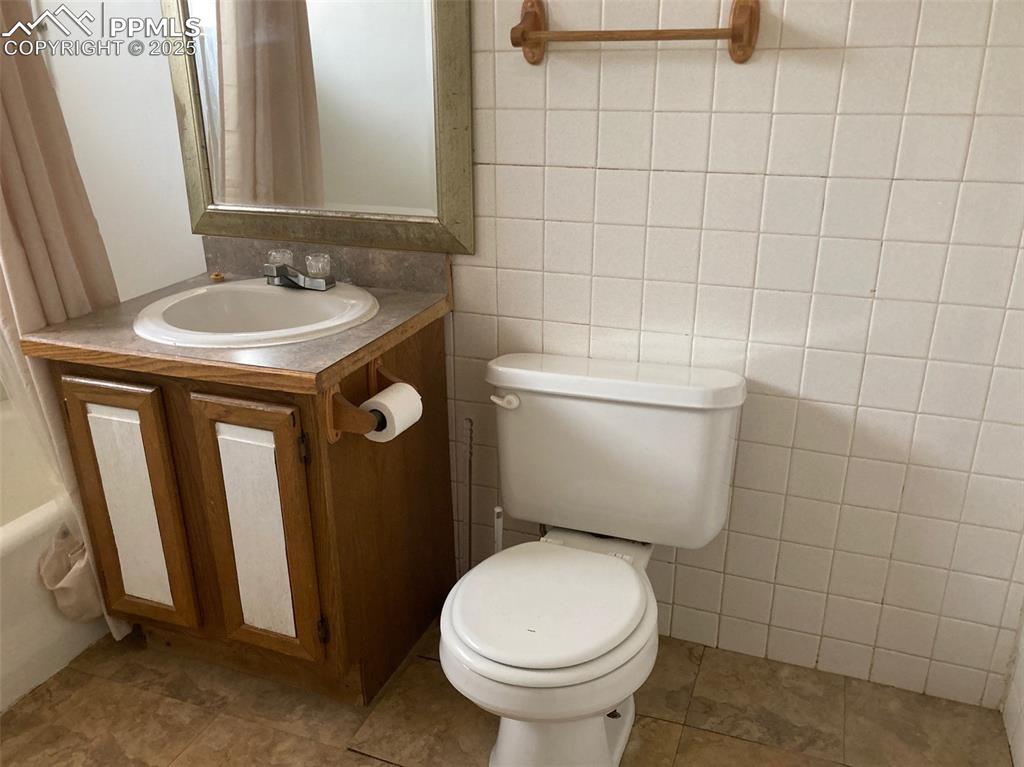 Image 9 of 11: Full bathroom with vanity, tile walls, and tile patterned floors