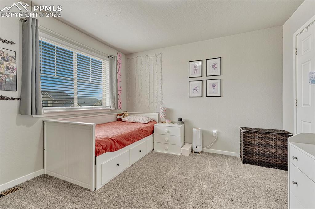 Image 22 of 50: Upper Level Bedroom #1 with neutral carpet and a large view window with bli