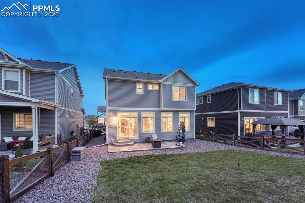 Image 35 of 50: Sunset rear view of home, backyard, and patio.
