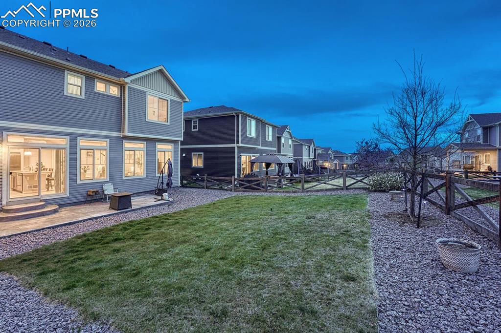 Image 36 of 50: Sunset view of backyard grass area surrounded by xeriscaped beds.