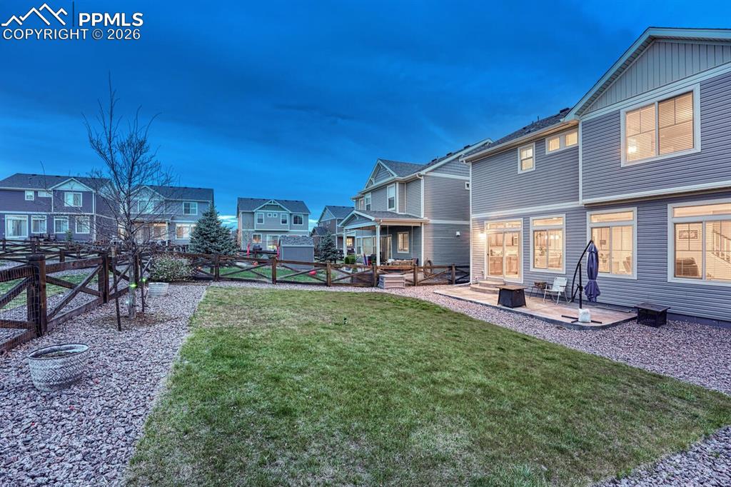 Image 7 of 50: The fenced Backyard has a generous stretch of green grass surrounded by xer