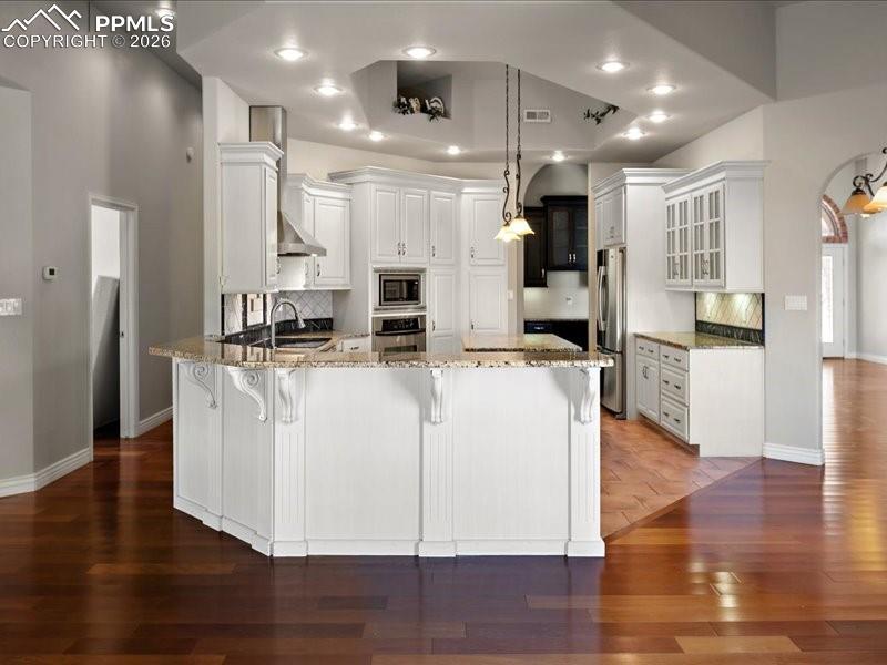 Image 22 of 48: Kitchen featuring light stone counters, a peninsula, dark wood-style floors