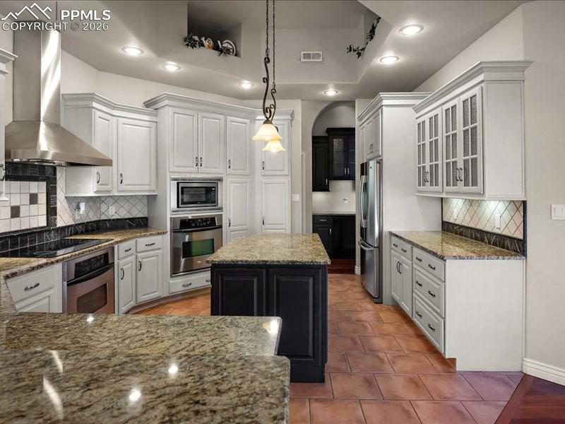Image 23 of 48: Two tone kitchen featuring decorative backsplash, dark stone countertops, s