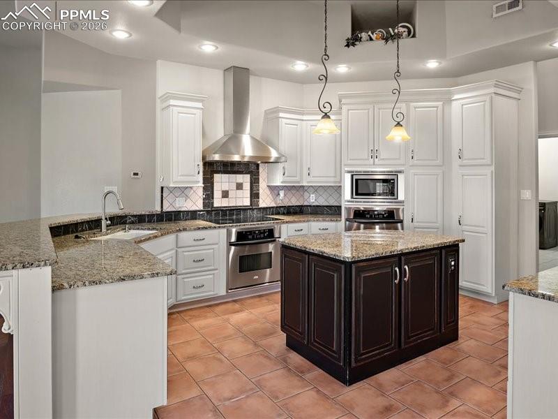 Image 24 of 48: Two tone kitchen featuring light stone counters, stainless steel appliances