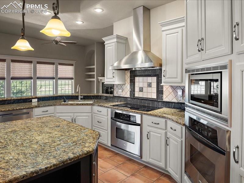 Image 26 of 48: Kitchen featuring pendant lighting, white cabinets, light stone counters, s