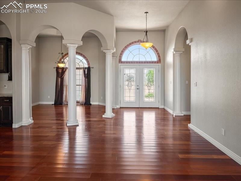 Image 4 of 48: Entryway featuring french doors, ornate columns, dark wood finished floors,