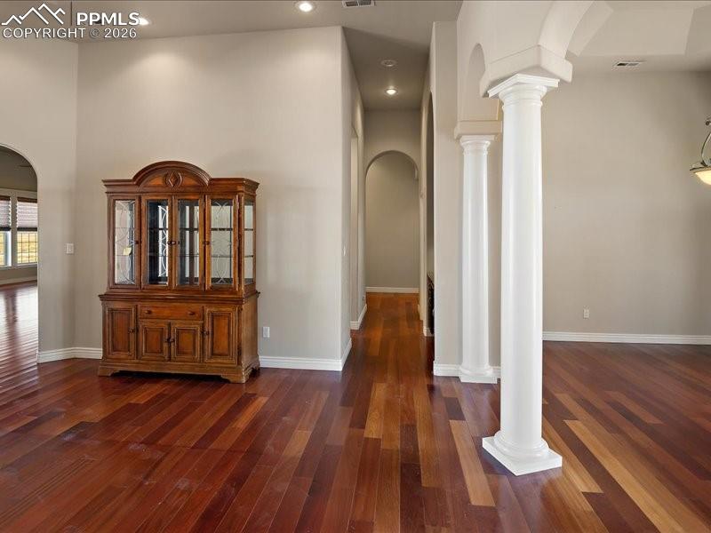 Image 6 of 48: Hall with arched walkways, decorative columns, dark wood-style flooring, an