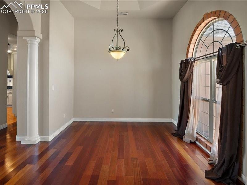 Image 7 of 48: Spare room featuring ornate columns, arched walkways, and dark wood-type fl