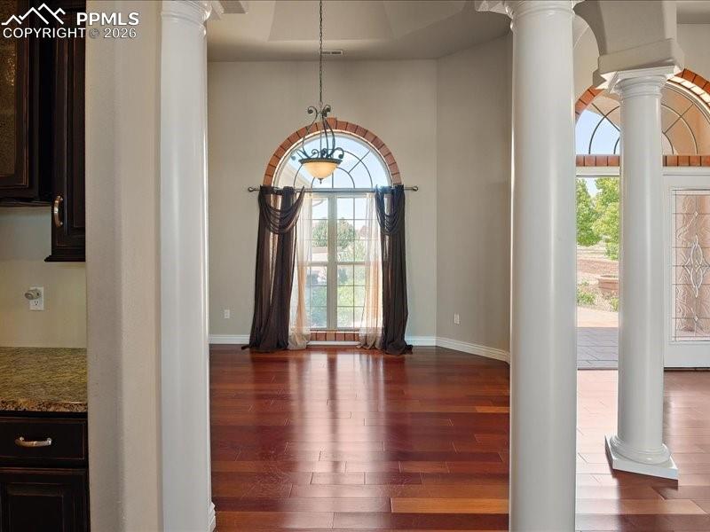 Image 8 of 48: Foyer entrance featuring decorative columns, dark wood-style flooring, plen