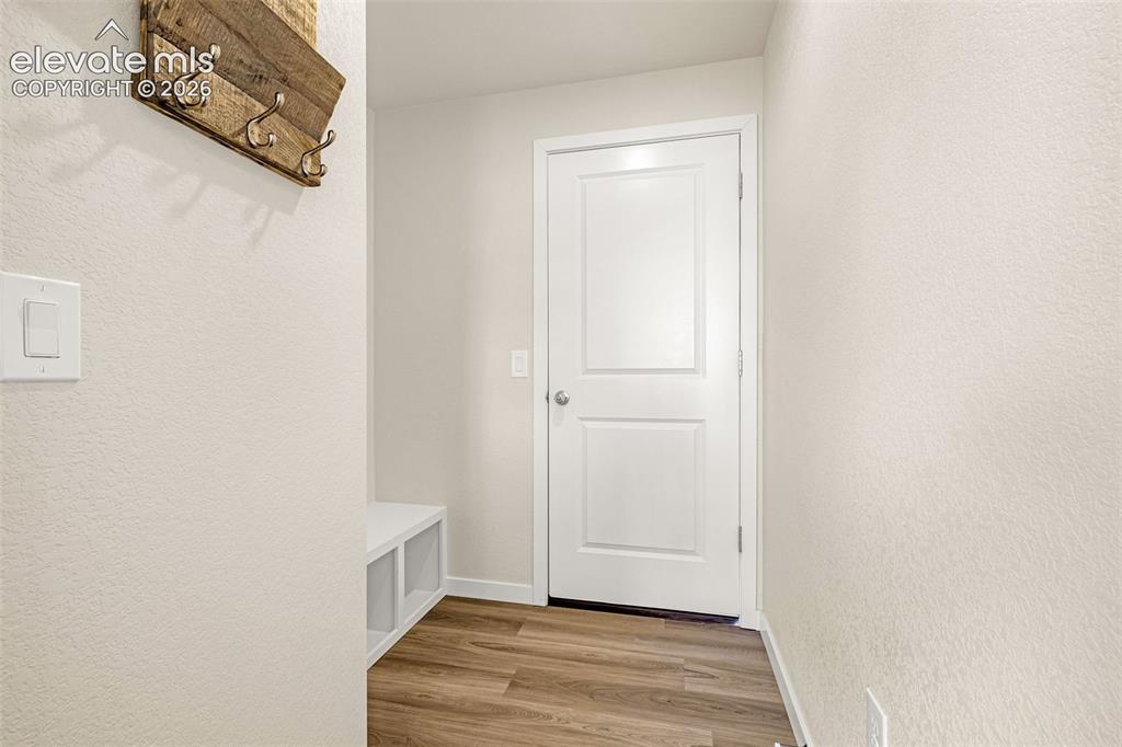 Image 14 of 50: Wood-finish flooring with white trim, featuring a white door and built-in s
