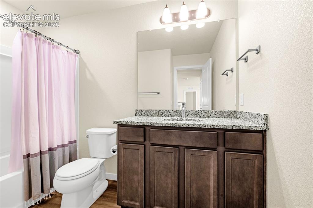 Image 22 of 50: Bathroom featuring a vanity with a stone countertop, dark wood-finish cabin