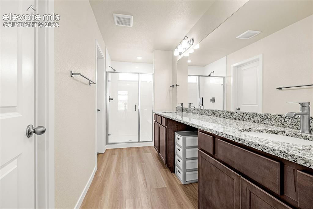 Image 25 of 50: Dual vanity with granite-style countertop and undermount sinks, wood-finish