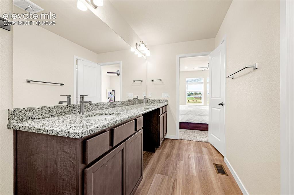 Image 26 of 50: Double vanity with granite countertop, dual sinks, wood-finish flooring, an