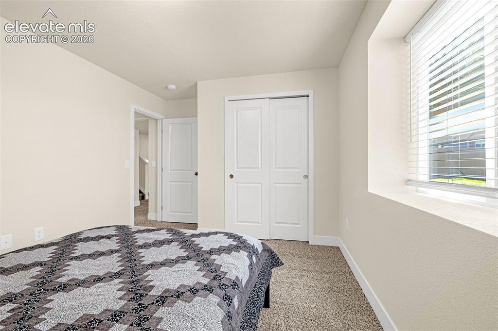 Image 31 of 50: Recessed window with blinds, bi-fold closet doors, and neutral carpeting