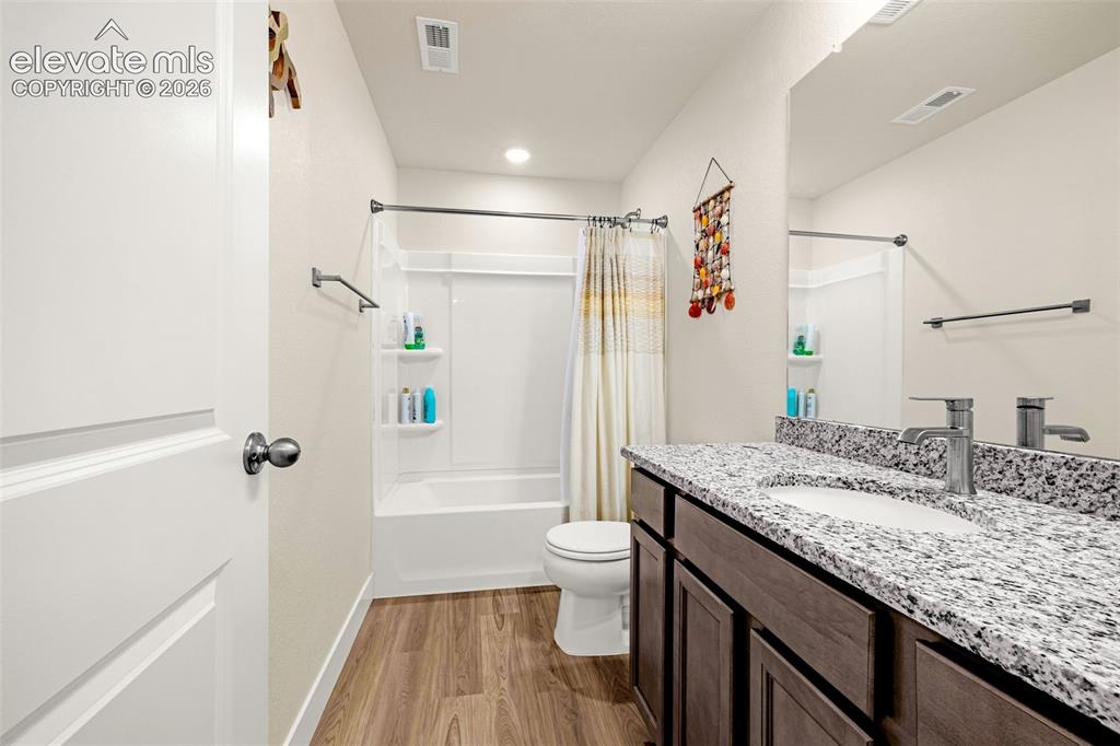 Image 32 of 50: Bathroom featuring wood-finish flooring, a white tub-shower combination, a 