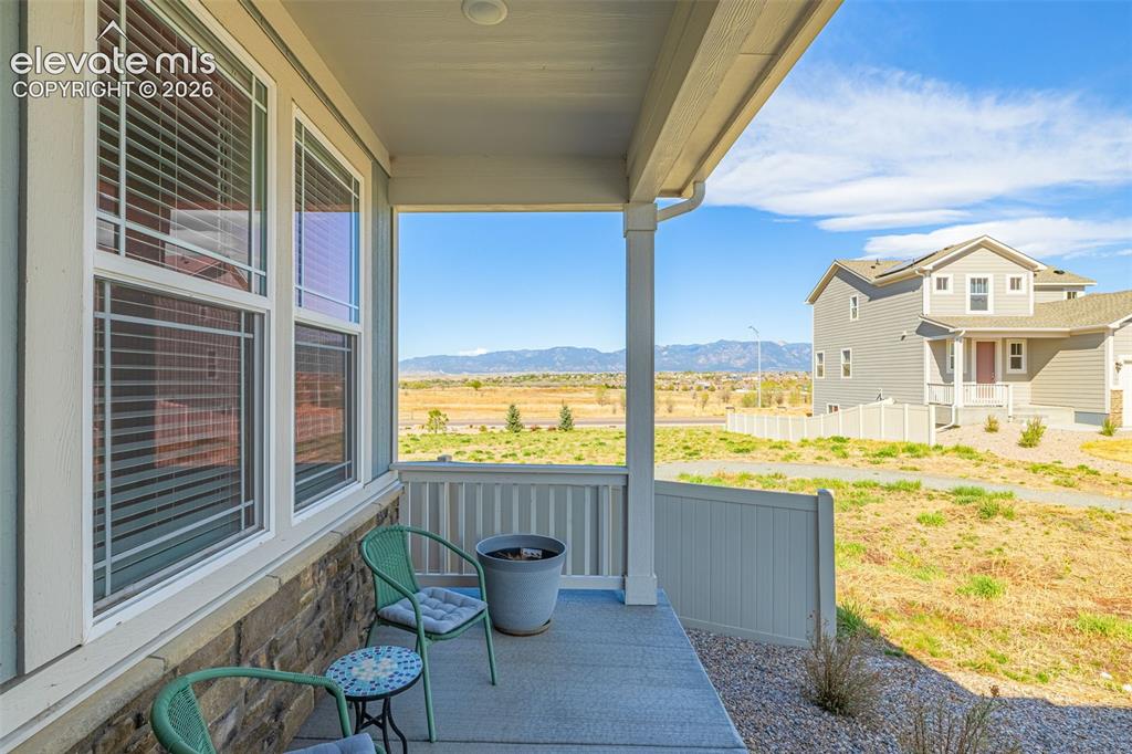 Image 37 of 50: Covered porch with concrete flooring, stone veneer siding, white vinyl rail