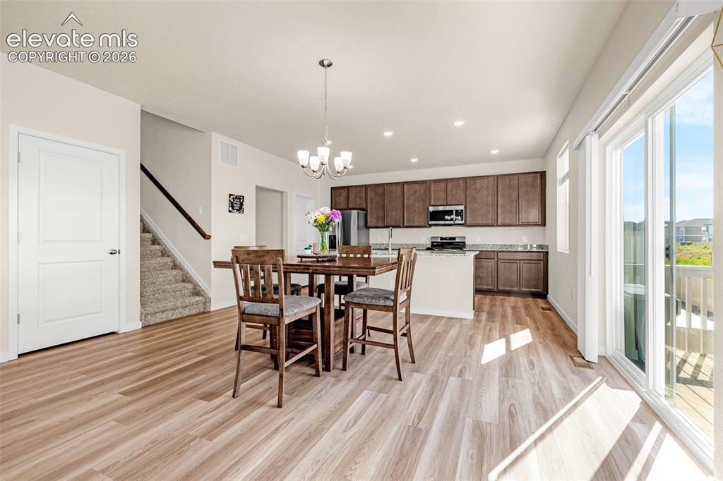 Image 4 of 50: Wood-finish flooring throughout, kitchen with dark wood cabinetry and light