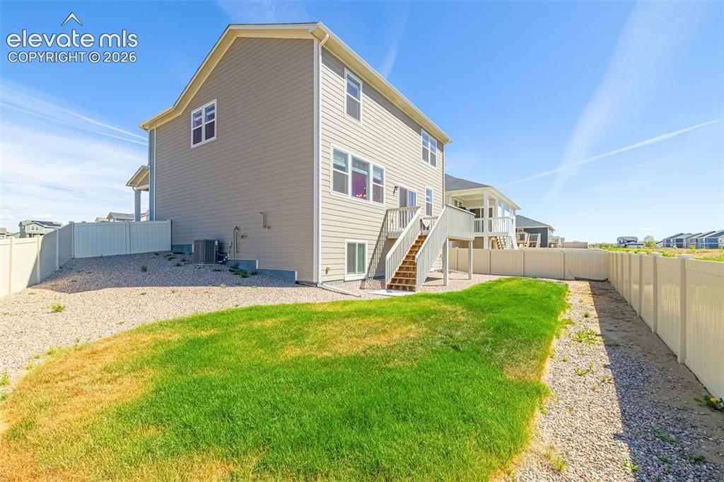 Image 40 of 50: Two-story exterior with siding, a wooden deck with stairs, a green lawn, an