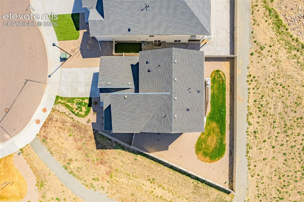 Image 44 of 50: Pitched roofline, concrete driveway, paved sidewalk, surrounding natural la